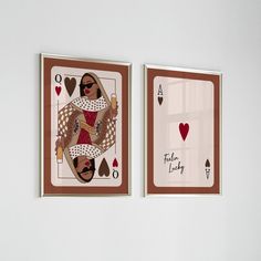 two playing cards are hanging on the wall next to each other, one has a woman holding a heart