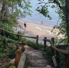 two people are walking down the stairs to the water's edge on a beach