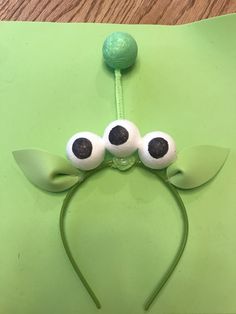 a green paper plate with googly eyes and a headband on top of it