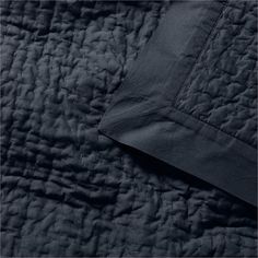 an image of a black quilted bedding with the sheets pulled back and folded down