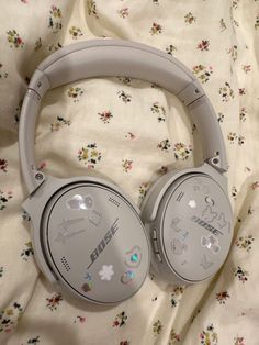 a pair of headphones sitting on top of a white bed sheet covered in flowers