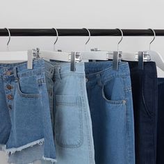 four pairs of jeans hanging on a clothes rack with clothing hangers in front of them