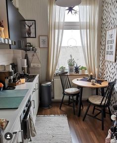 a kitchen with a table and chairs next to a window in the room that has curtains on the windowsill