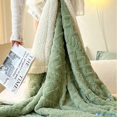 a woman standing on top of a bed covered in a blanket and holding a newspaper