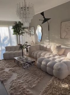 a living room filled with lots of furniture and a chandelier hanging from the ceiling