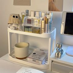 a white shelf filled with cosmetics and personal care items on top of a table next to a computer