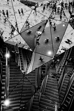 black and white photo of escalators with people walking on them in the city