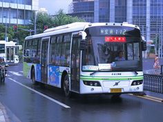 a city bus driving down the street in front of tall buildings on a rainy day