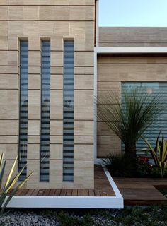 a modern house with wood and glass panels on the front door, along with landscaping