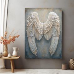 an artistic painting with white wings on a blue and gray background in a living room