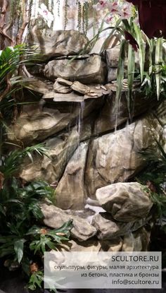 a waterfall in the middle of some rocks and plants