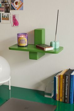 a laptop computer sitting on top of a green shelf next to a white chair and bookshelf