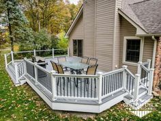 a deck with table and chairs in front of a house