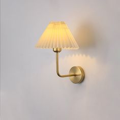 a wall light with a white shade on it's side and the lamp turned off