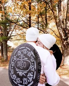 two people in white hats hugging each other and holding an oreo cookie on the road