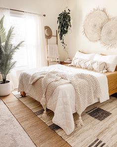 a bedroom with a bed, rugs and potted plants