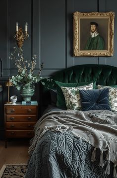 a bed with green velvet headboard and pillows in front of a painting on the wall