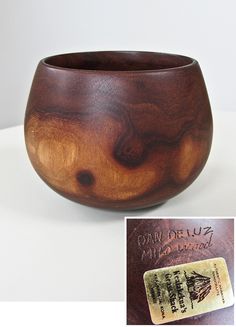 a wooden bowl sitting on top of a white table next to a brown leather book