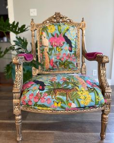 an ornately decorated chair sits in front of a potted plant