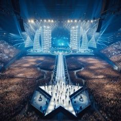 an aerial view of a concert venue with stage lighting and large crowd in the foreground