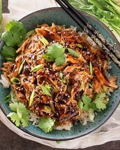 a bowl filled with meat and rice next to chopsticks