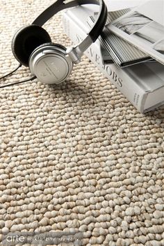 a pair of headphones sitting on top of a carpet next to a pile of books