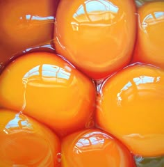 many orange balls are stacked together in the middle of a bowl with water on top