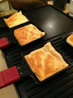 four pans filled with food sitting on top of a stovetop next to a red spatula