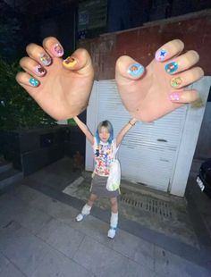 a girl holding her hands up in front of a garage door with painted nails on it