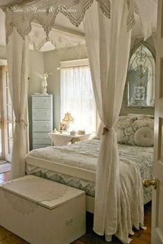 a white bed sitting in a bedroom next to a dresser under a window with curtains