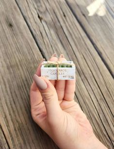 a person holding two small pieces of food in their hands on a wooden table with wood planks