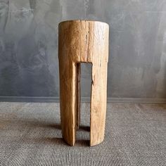 a wooden stool sitting on top of a carpeted floor next to a gray wall