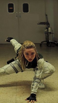 a woman is doing a handstand on the floor in an empty room with other equipment