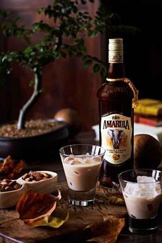 a bottle of ambarella next to bowls of nuts and other foods on a table