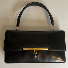 Hermes Palonnier Handbag In A Smooth Black Leather. Leather Shows Scratches And Corner Wear Consistent With Older Bag. Single Flat Top Handle With 5.5 Inch Drop. Creasing On Handle Leather. Dark Gold Tone Hardware With Tarnish. Front Top Flap With Hook Clasp Closure. Leather Lined Interior With Four Compartments - A Large Gusset Pocket, A Rear Slip Pocket Behind A Snap Closure Pouch And A Front Slip Pocket. Gold Embossed Hermes Paris Stamp. No Box Or Dust Bag. An Oldie But A Goodie In A Vintage Paris Stamp, Hermes Clutch, Hermes Paris, Dark Gold, Hermes Bags, Hook Clasp, Pocket Book, Flats Top, Snap Closure