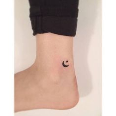 a small black star and crescent tattoo on the right side of the ankle, with a tiny white dot in the middle