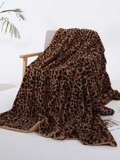 a leopard print blanket sitting on top of a chair next to a potted plant