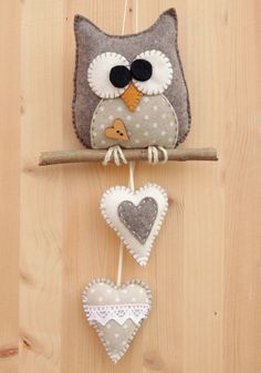 an owl is hanging on the wall with two heart shaped ornaments in front of it