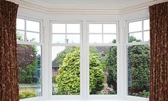 an open window with curtains in front of it and a view of the garden outside