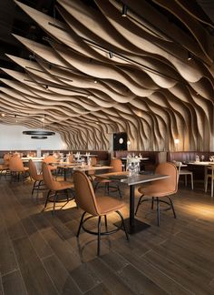 the interior of a restaurant with wooden walls and tables, orange chairs, and wood flooring