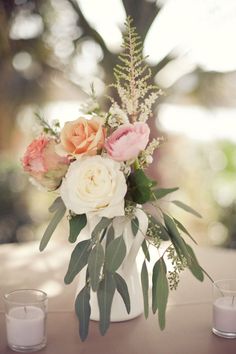 a vase filled with flowers sitting on top of a table next to two votive candles