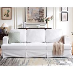 a white couch sitting in a living room on top of a rug