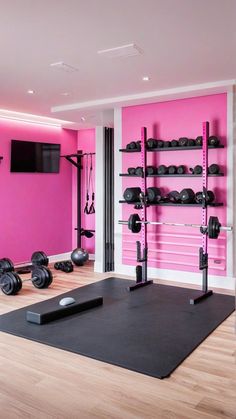 a gym with pink walls and black exercise mats in front of the wall is an exercise equipment rack