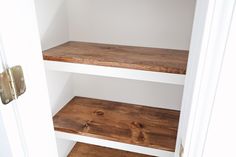 an open closet with three wooden shelves in it