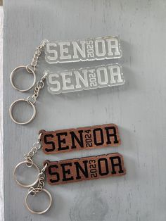 two wooden keychains with the words senior and senior printed on them sitting next to each other