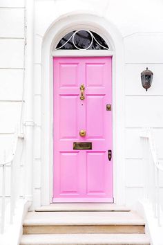 a bright pink door sits in front of a white house