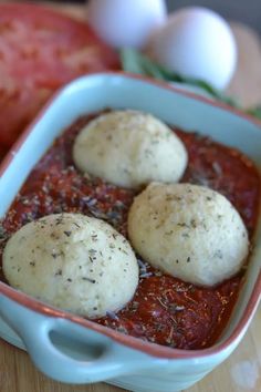 three balls of bread sit in a blue casserole dish on a wooden table