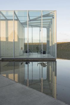 an empty glass building sitting on top of a body of water