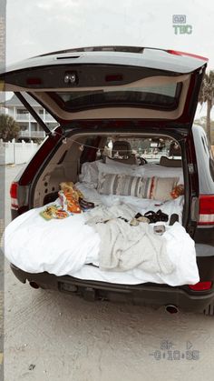 the back end of a car with its trunk open and blankets on it's bed