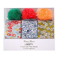 four assorted tissue boxes with pom - poms on them in a box